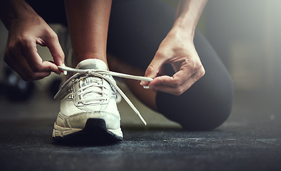 Image showing Woman tie shoe laces, hands and fitness with athlete in gym and sports with training for health. Closeup of runner sneakers, start workout in exercise studio with healthy and active female person