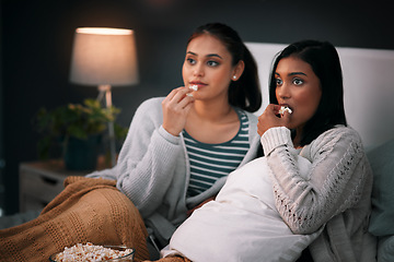 Image showing Popcorn, eating and women or friends with horror movies, scary show and sleepover on bed, streaming service or television. Gen z people relax in bedroom for drama TV film, home cinema or subscription