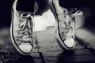 Image showing Balance, shoes or fashion in grayscale on an urban street outdoor for dance or contemporary style. Feet, sneakers or footwear in black and white in a city to explore for travel, tourism or adventure