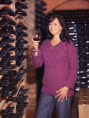 Image showing Portrait, mature woman and red wine in a cellar, smile and confident lady with success, joyful and celebrate. Face, happy female person and business owner with happiness, alcohol and wellness