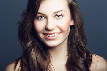 Image showing Cosmetic, beauty and portrait of a woman in a studio with a natural, facial and skincare routine. Happy, smile and face of a young female model with makeup or dermatology treatment by blue background