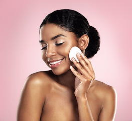 Image showing Skincare, mockup and happy woman with cotton pad on face, smile and makeup removal with skin product in studio. Dermatology, facial cleansing cosmetics and African model isolated on pink background.