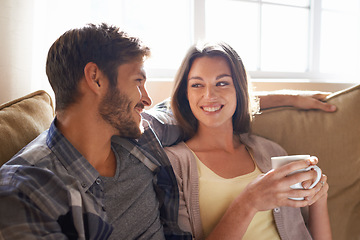 Image showing Coffee, love and couple smiling at each other or on a couch in the living room or bonding and conversation. Man, woman and communicating or affectionate with hot beverages or happy partners at home