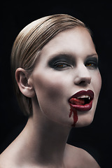 Image showing Portrait, blood and a woman vampire in studio on a dark background for halloween or cosplay. Fantasy, horror or scary with an attractive young female monster posing as an evil and feminine creature