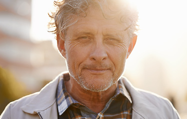 Image showing Portrait, sunset and a senior man in the city during the day for travel or tourism during retirement. Face, wrinkles and lifestyle with a handsome male person standing outdoor in an urban town flare