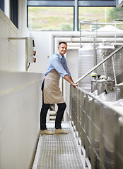 Image showing Industry, confidence and portrait of a wine maker standing by stainless steel machines in factory. Proud, smile and full length of a male winery employee doing alcohol production in cellar warehouse.