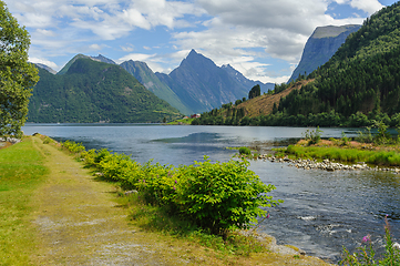 Image showing path by a river that flows into the sea with mountains in the ba