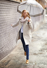 Image showing Rain umbrella, city street and woman jump with happiness on a sidewalk from winter weather. Happy female person, raining and travel on urban road outdoor in Cape Town on holiday with freedom and joy