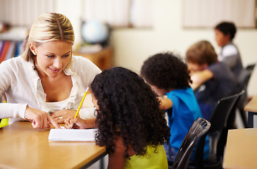 Image showing School, education or learning with a teacher and student in a classroom during a lesson for child development. Study, kids or writing with a woman educator helping a girl pupil while sitting in class