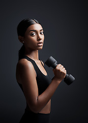 Image showing Portrait, serious and woman with dumbbell for exercise in studio isolated on black background. Strong, bodybuilder and female athlete with weight for muscle, strength or fitness, workout or training.