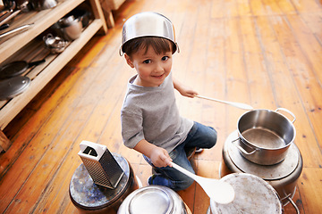 Image showing Portrait, fun and boy child playing drums on pans on a floor, happy and enjoying music. Face, creative and kid with pots for musical entertainment, silly and carefree in a kitchen on the weekend