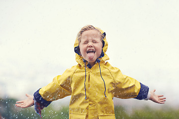 Image showing Winter, raincoat and a girl playing in the rain outdoor alone, having fun during the cold season. Kids, water or wet with an adorable little female child standing arms outstretched outside in the day