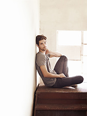 Image showing Portrait, depression and alone with a man on a staircase in his home, sitting on the landing by a window. Lonely, mental health and relax with a handsome young male on steps or stairs in his house