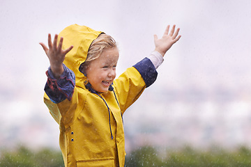 Image showing Winter, raincoat and a girl having fun in the water outdoor alone, playing during the cold season. Kids, rain or wet with an adorable little female child standing arms outstretched outside in the day