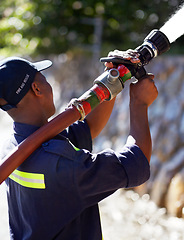 Image showing Firefighter man, water and spraying hose for emergency, rescue or firefighting services in the outdoors. Fireman using big liquid pressure pipe to spray down or put out fire outside for safety