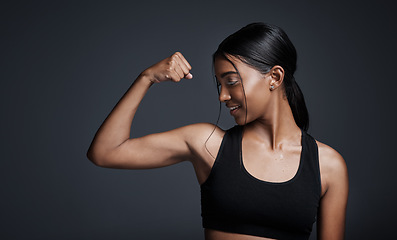 Image showing Sports, smile and woman flexing bicep in studio isolated on black background. Strong, happy and Indian female athlete with muscle, arm strength and bodybuilder ready for fitness, workout or exercise.