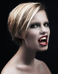 Image showing Portrait, fangs and a woman vampire in studio on a dark background for halloween or cosplay. Fantasy, horror and scary with an attractive young monster posing as an evil or supernatural creature