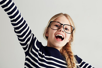 Image showing Happy, excited and portrait of young girl with happiness to celebrate isolated in a white studio background. Glasses, vision and female kid smile with freedom in a strip t-shirt for child fashion