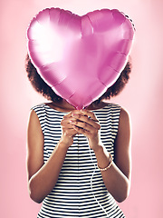 Image showing Woman cover face with heart balloon in studio, pink background and celebrate surprise birthday party. Female model hide with helium, gift and present for love, valentines day and secret celebration