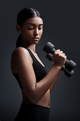 Image showing Sports, serious and woman with dumbbell for workout in studio isolated on a black background. Strong, bodybuilder and Indian female athlete weightlifting for muscle, training and fitness exercise.