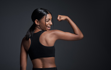 Image showing Wink, happy and woman flexing muscle in studio isolated on a black background mockup. Strong flex, funny and Indian female athlete with bicep, arm strength or bodybuilder back, fitness or workout.