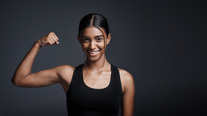 Image showing Portrait, smile and woman flexing bicep in studio isolated on a black background mockup space. Strong, happy and female athlete with muscle, arm strength and bodybuilder ready for fitness workout.