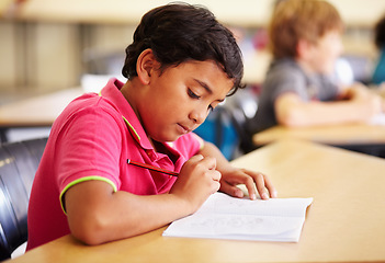 Image showing Education, student and boy in a classroom, writing and studying for a test, exam and notebook. Male child, school and kid with a book, pencil and creative with development, growth and learning