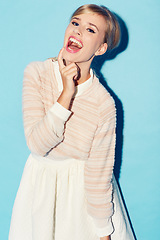 Image showing Portrait, comic and comedy with a woman in studio on a blue background for fun or laughter. Fashion, laugh and humor with an attractive young female model laughing a funny joke against a color wall