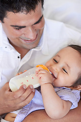 Image showing Baby laugh, feeding and dad with child at home with a bottle of milk with happiness with kids. Family, young child and drink for growth and development with father bonding and happy in a house