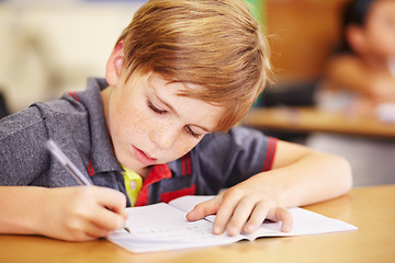 Image showing Education, student and boy writing, focus and learning with creativity, book and reading. Male person, child and kid in school, classroom and knowledge with exam, future and test for development