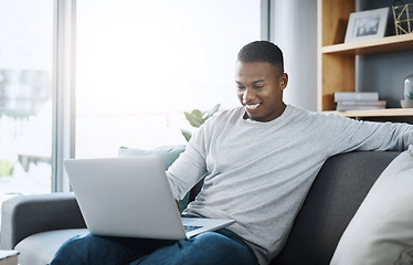 Image showing Black man with laptop, streaming online and relax in living room, subscription service with internet and happiness. Technology, connectivity and male person chill at home watching movie on sofa