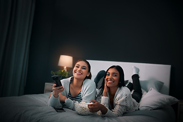 Image showing Women friends on bed at night for movies, eating popcorn and happy sleepover at home with streaming service or television. Gen z people relax in bedroom with TV film, cinema subscription and internet