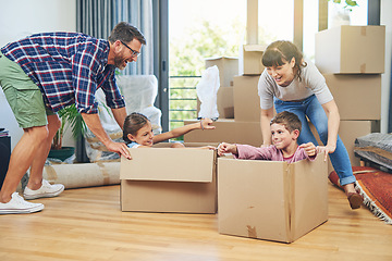 Image showing Child, happiness and boxes with family moving in apartment for fun and enjoyment on the floor. Parents, happy and children excited in a box at family home for investment and a lifestyle with love.