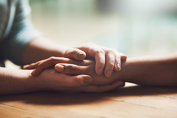 Image showing Love, empathy and support with people holding hands in comfort, care or understanding on a wooden table of a home. Prayer, faith or depression with friends closeup for hep, hope or peace for healing