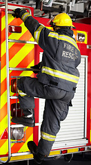 Image showing Firefighter, man and climbing ladder for emergency operation, service or rescue with equipment. Fireman person with helmet, jacket and gear protection getting on truck for firefighting at station