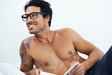 Image showing Book, happy shirtless young man with glasses and on a bed in white background. Nerd or smart, male model with sexy body and smiling person topless in his home or apartment with notebook for reading