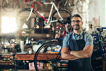 Image showing Portrait, smile and repair man in bicycle shop with arms crossed working in store. Face, bike mechanic and confident male person from Canada with happiness, glasses and mature in cycling workshop.