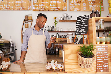 Image showing Man, coffee shop and phone of a waiter with happiness from small business. Cafe, mobile and African barista entrepreneur looking on online order app with smile at bakery and restaurant feeling happy