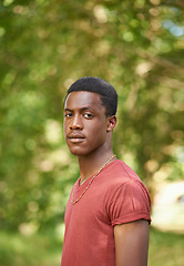 Image showing Portrait, teen boy and outside in garden with bokeh blurred background or African teenager, nature and outdoor, park or summer. Young person, serious face and green, trees or spring sunshine