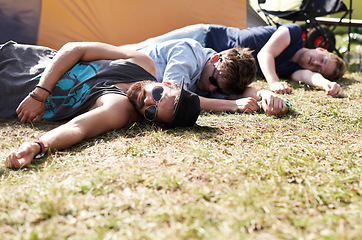 Image showing Drunk sleeping, hangover and party people on camping park at music festival with alcohol. Field, ground and lawn with a tent and youth on grass with male friends and man camper at concert outdoor