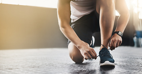 Image showing Sports, athlete and man tie shoes in a gym before workout for health, wellness and endurance training. Fitness, sneakers and closeup of male person tying laces to start a exercise in sport center.