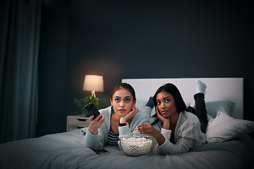 Image showing Girls night, young women and popcorn while watching television on a bed in bedroom. Relaxing or entertainment, fun and female friends with snack with streaming movie or series together at home