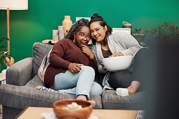 Image showing Girl friends, shocking movie and home living room laughing on a couch with a happy smile. Tv, relax and women together in a lounge with a female friend looking at a television in house with popcorn