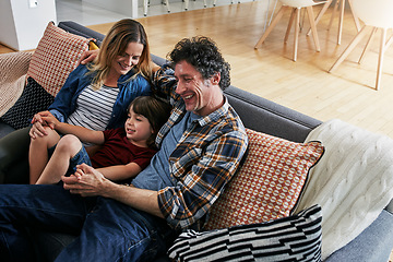 Image showing Mom, dad and child smile on sofa in living room for love, care and fun quality time together in family home. Happy young boy, cute kid and relax with parents in lounge, happiness and bonding on couch
