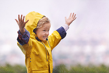 Image showing Girl, outdoor and playing in rain with happiness, hands and freedom in backyard, park or garden. Young female child, open palm and excited face with raincoat, winter fashion and playful in raindrops