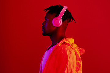 Image showing Headphones, neon fashion and black man profile with music and online song streaming. Internet radio, web audio and African male model with red background in a studio with gen z style and clothing