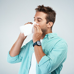 Image showing Blowing nose, tissue and man in studio with allergy, sickness and virus infection on white background. Health, wellness and face of male person with handkerchief for hayfever, cold and sneeze for flu