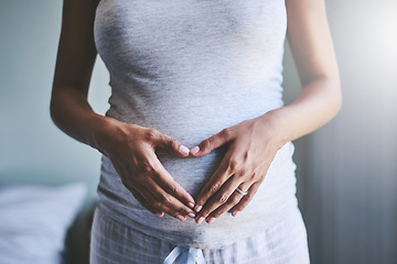 Image showing Pregnant woman with a heart shape on her belly for love, care and maternity in her house. Bonding, maternal and closeup of a female person holding her pregnancy stomach for motherhood at her home.