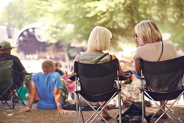 Image showing Back, friends sitting and outdoor festival on camping chair, talking and women in audience, concert or music performance. People, fans relaxing together or summer show, entertainment or culture event