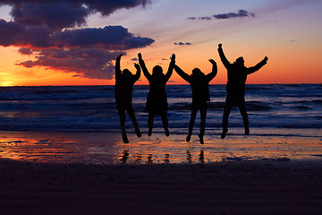 Image showing Sunset, beach and silhouette of jumping friends in nature, freedom and celebrating travel outdoor. Shadow, jump and group of people at the ocean at sunrise for adventure, celebration or sea vacation